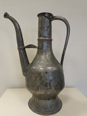 Старинный металлический кувшин ручной работы с фигурным носиком и изящной перемычкой-мостком. 