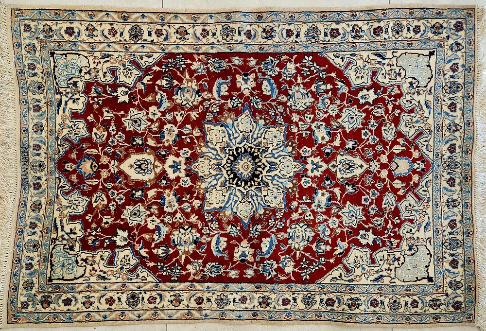 שטיח נעין פרסי, 
דוגמת מדליון מרכזי בצורת כוכב, 
פרחים ועיטורים על רקע אדום במרכז ולבן בשוליים. 