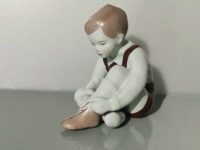 נער וינטג' עם שרוכי נעליים, אקווינקום 
פסל פורצלן הונגרי מבודפשט 
גודל - כ- 11 ס"מ x 9 ס"מ x 