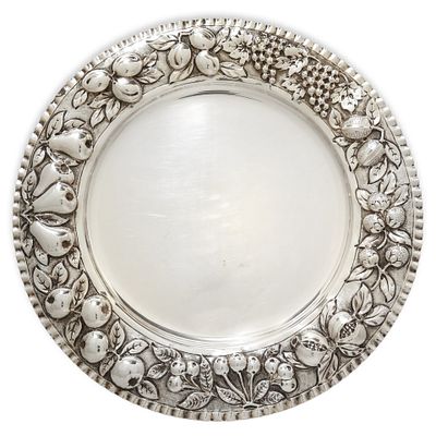 Piatto centrotavola in argento 800 con decorazioni a sbalzo di melagrane lungo il bordo lungo 