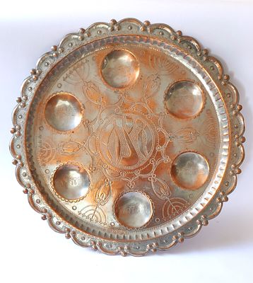 קערת פסח ענקית מנחושת אדמדמה. מלאכת ריקוע מצויינת בחומר. מעוטרת מאוד במנורות שבעת הקנים. יש וו 