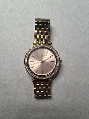 שעון לאישה או יוניסקס MICHAEL KORS מוזהב. משובץ שבבי יהלומים זעירים. לוח בגוון שמפניה ורודה. 