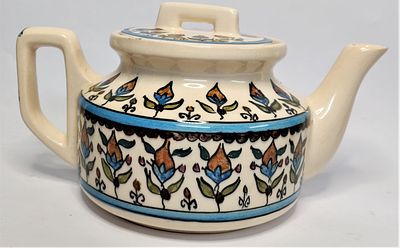 קנקן קרמיקה מזוגגת ומצוירת בסגנון ארמני. אלמנטים פרחוניים בהיקף, במכסה ובידית. 
חתום: חורש ירושלים.