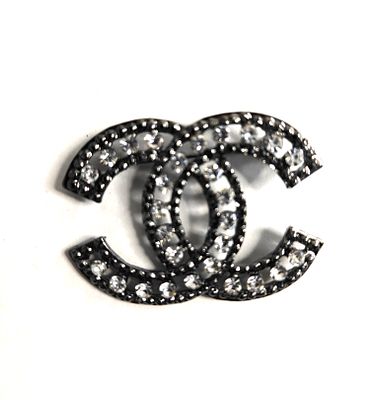 סיכה בעיצוב הלוגו של "שאנל" CHANEL מעוטר בשבבי זכוכית.