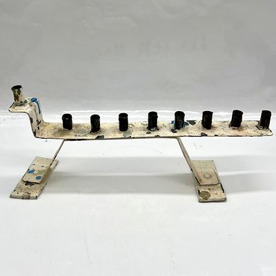 חנוכיה ממתכת עבודת יד . מידות: גובה 12.5 ס״מ, רוחב 28 ס״מ