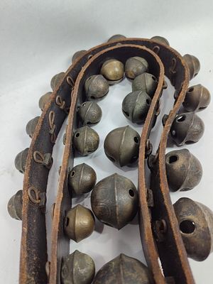 Strand of double graduated brass sleigh bells. 33 brass bells on leather belt.