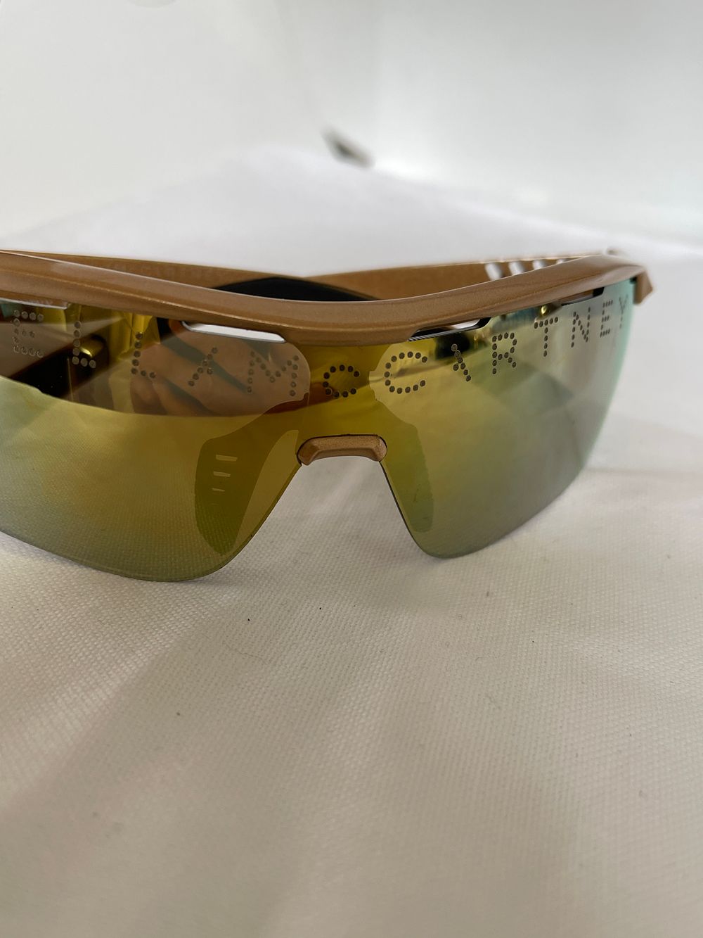 Lot 180: Sporty Stella McCartney sunglasses featuring a metallic gold lens showcasing the Stella McCartney logo. Designed for comfort with adjustable nose pads, this is the perfect pair of sport glasses. Frame Material: Bio Injection Frame: Metallic Gold Lenses: M