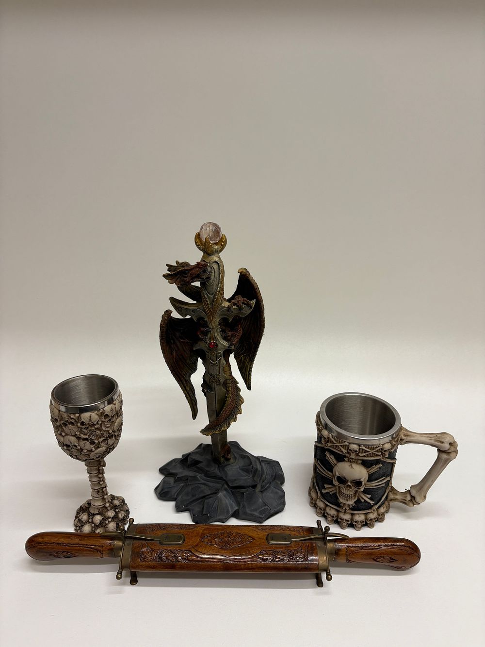 Lot 638: A Collection of Fantasy and Gothic Themed Decorative Items, including a Dragon Sculpture, a Dragon Skeleton Goblet, a Skull and Bone Mug, and a Carving Set