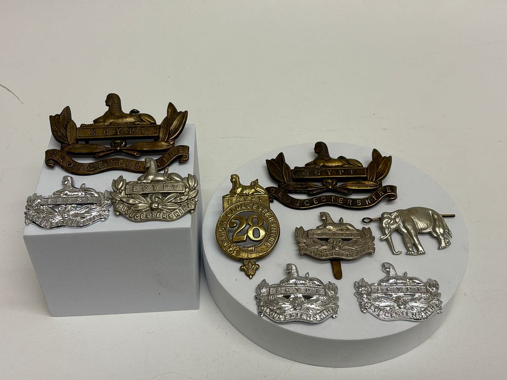 Lot 79: A Collection of Nine British Military Insignia, Gloucestershire Regiment Cap Badges