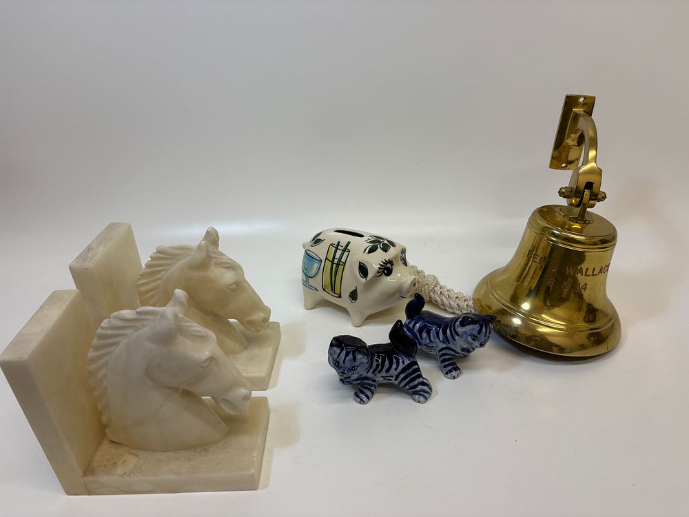 Lot 671: An Assortment of Decorative Items Including Carved Stone Horse Head Bookends, Delft Style Ceramic Figurines, and a Commemorative Brass Bell