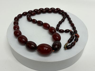 An Art Deco Style Graduate Cherry Red Amber Bead Necklace. A vintage graduated bead necklace 