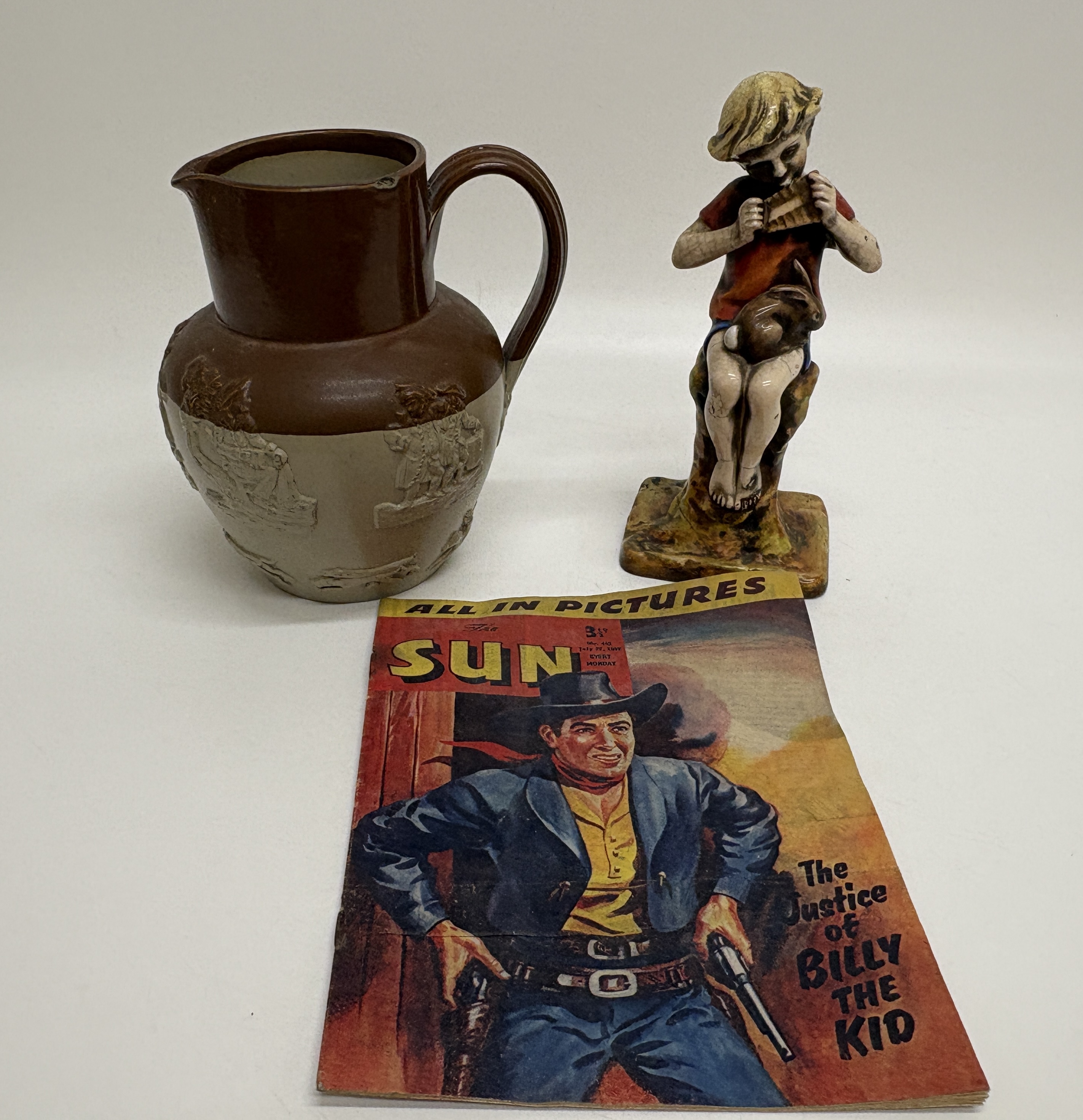 A Trio of items comprising a Royal Worcester Peter Pan figurine, a salt-glazed stoneware jug, and a 1957 copy of The Sun comic