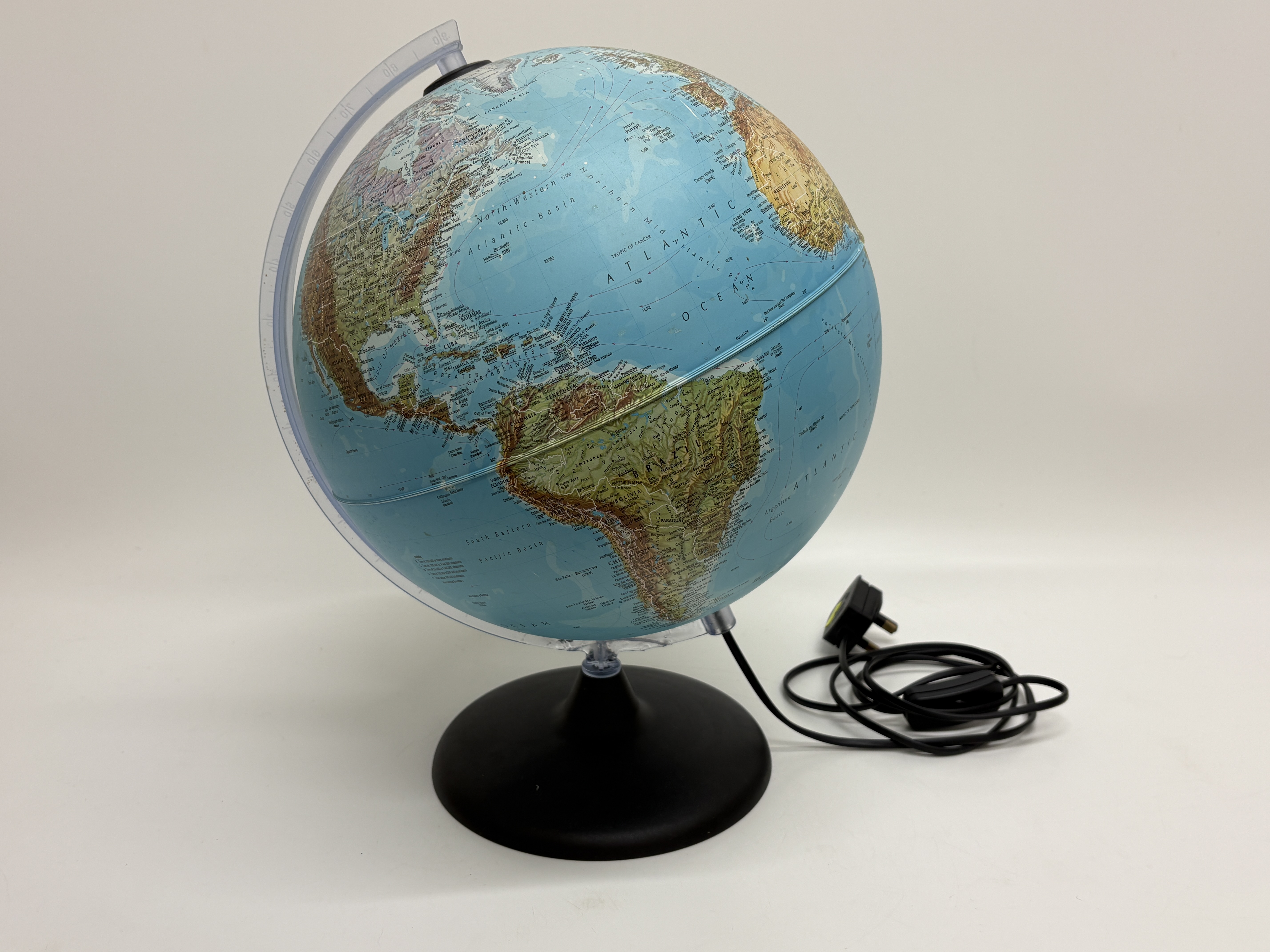 An illuminated dual-map table globe on a black circular base