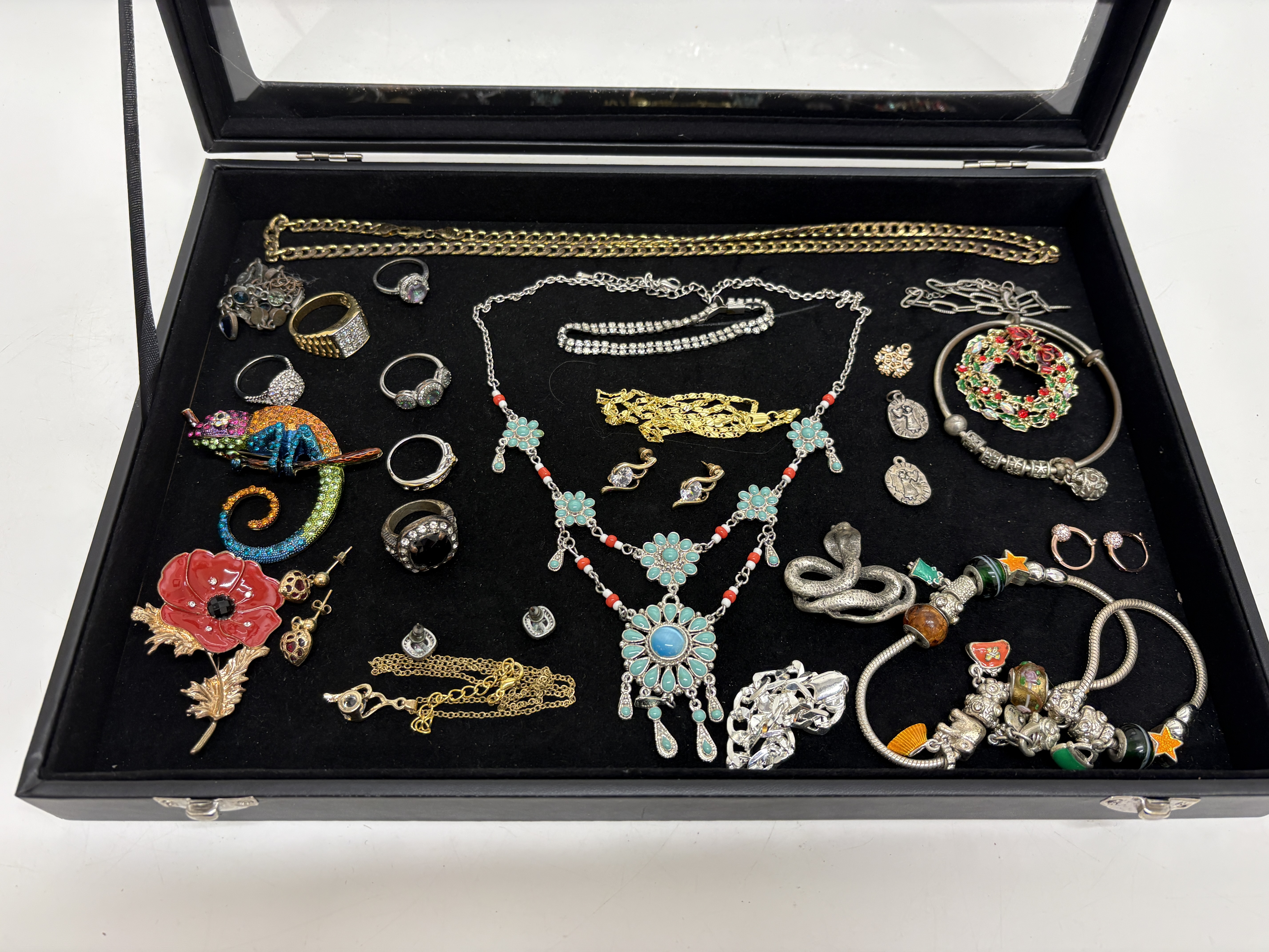 An Assortment of Costume Jewellery including Brooches, Rings, and a Charm Bracelet