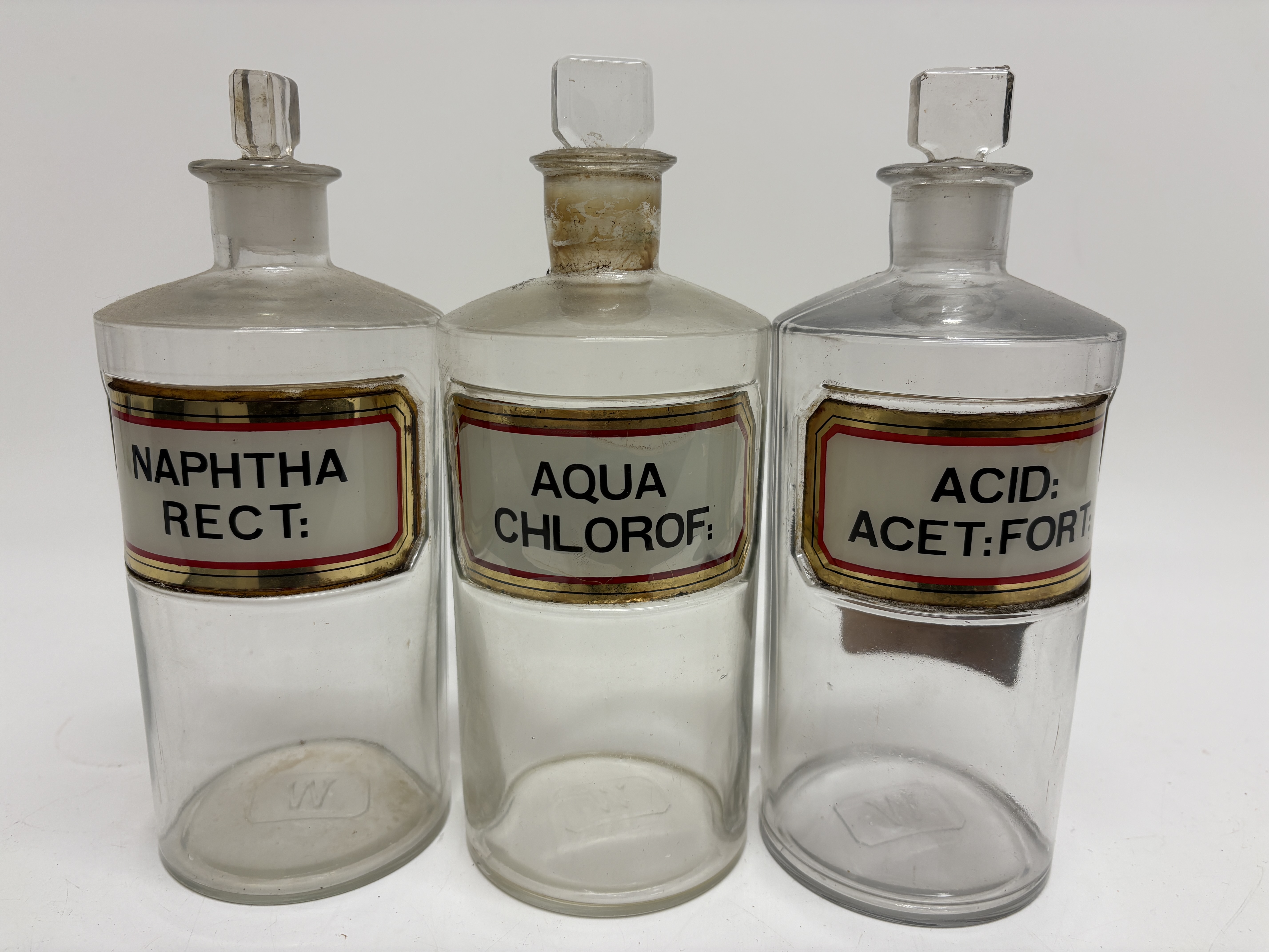 A trio of Wood Brothers clear glass apothecary shop round bottles with enameled labels 22mm tall