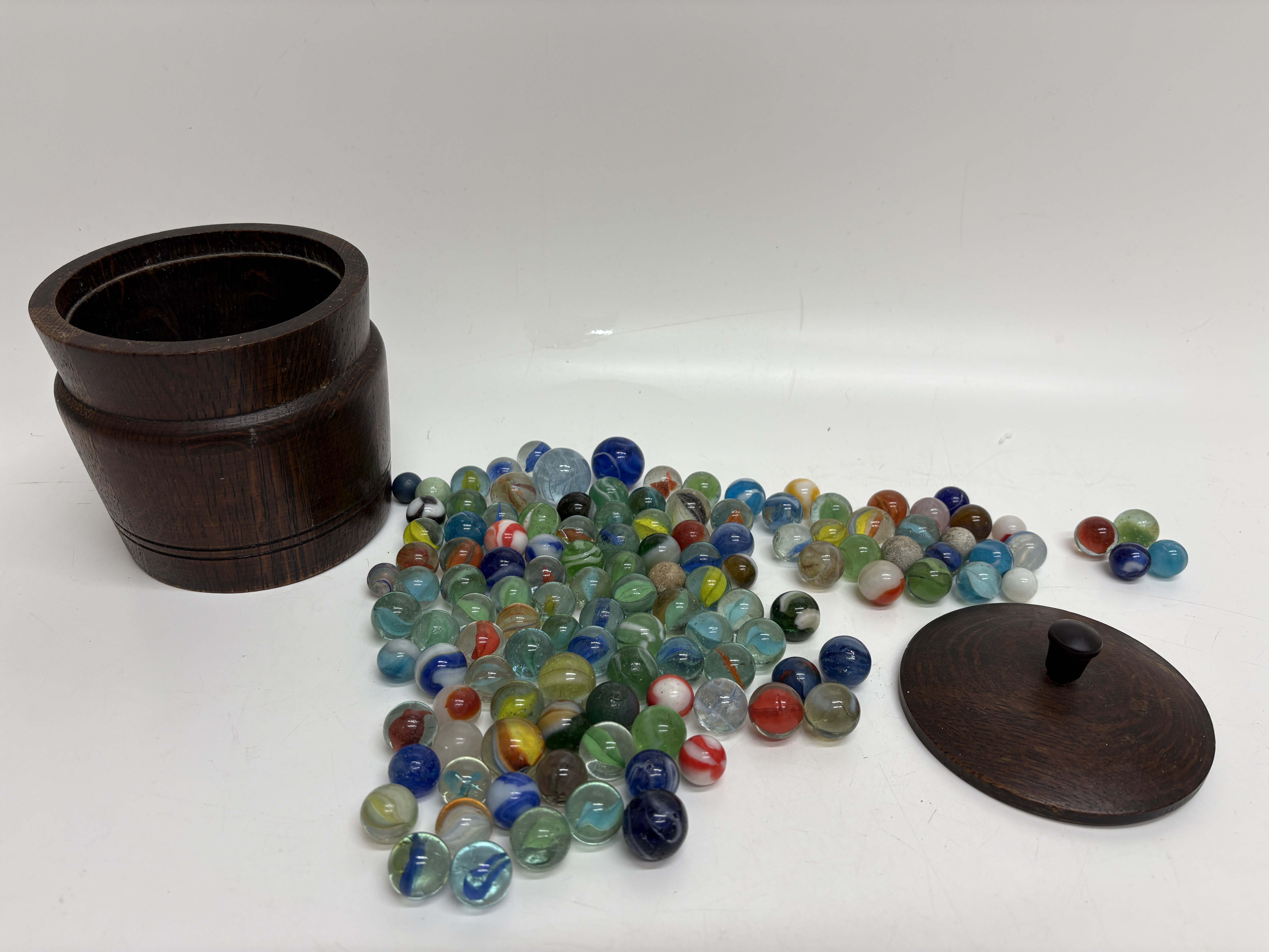 A Collection of Assorted Glass Marbles with a Turned Wooden Storage Jar