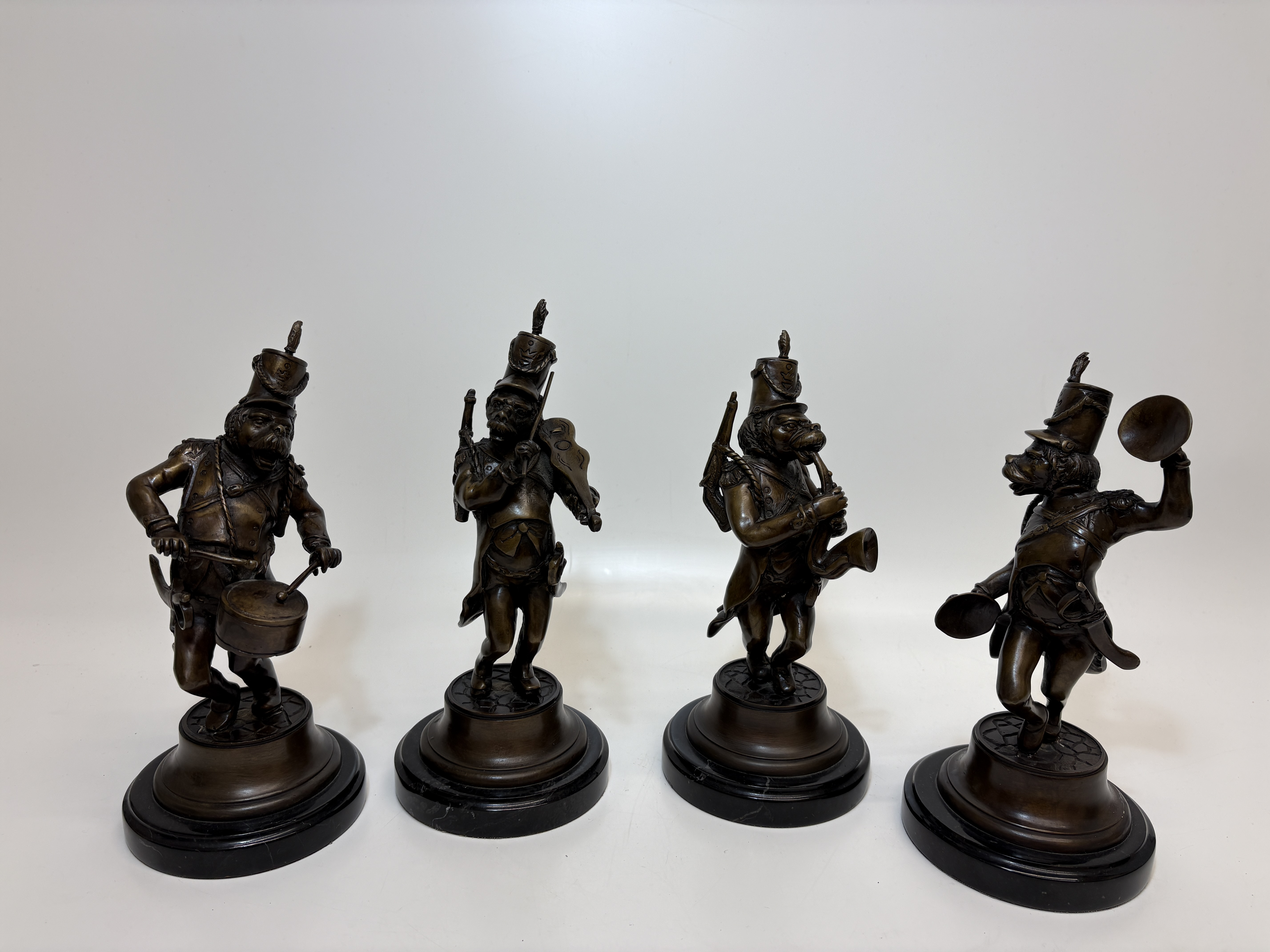 A Set of Four Bronze Military Dog Musicians on Marble Plinths