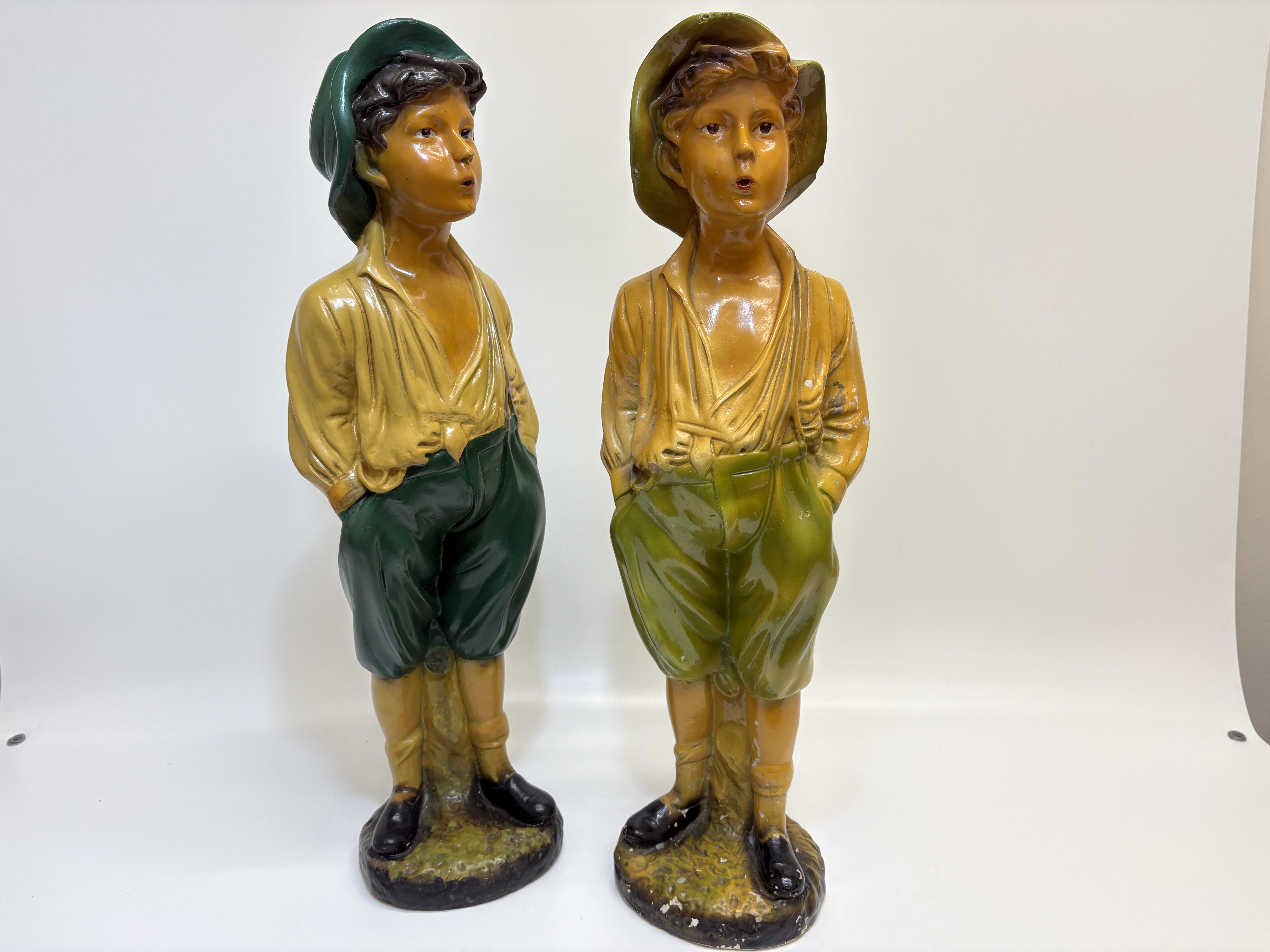 A pair of large painted composition whistling boy figurines 60cm tall