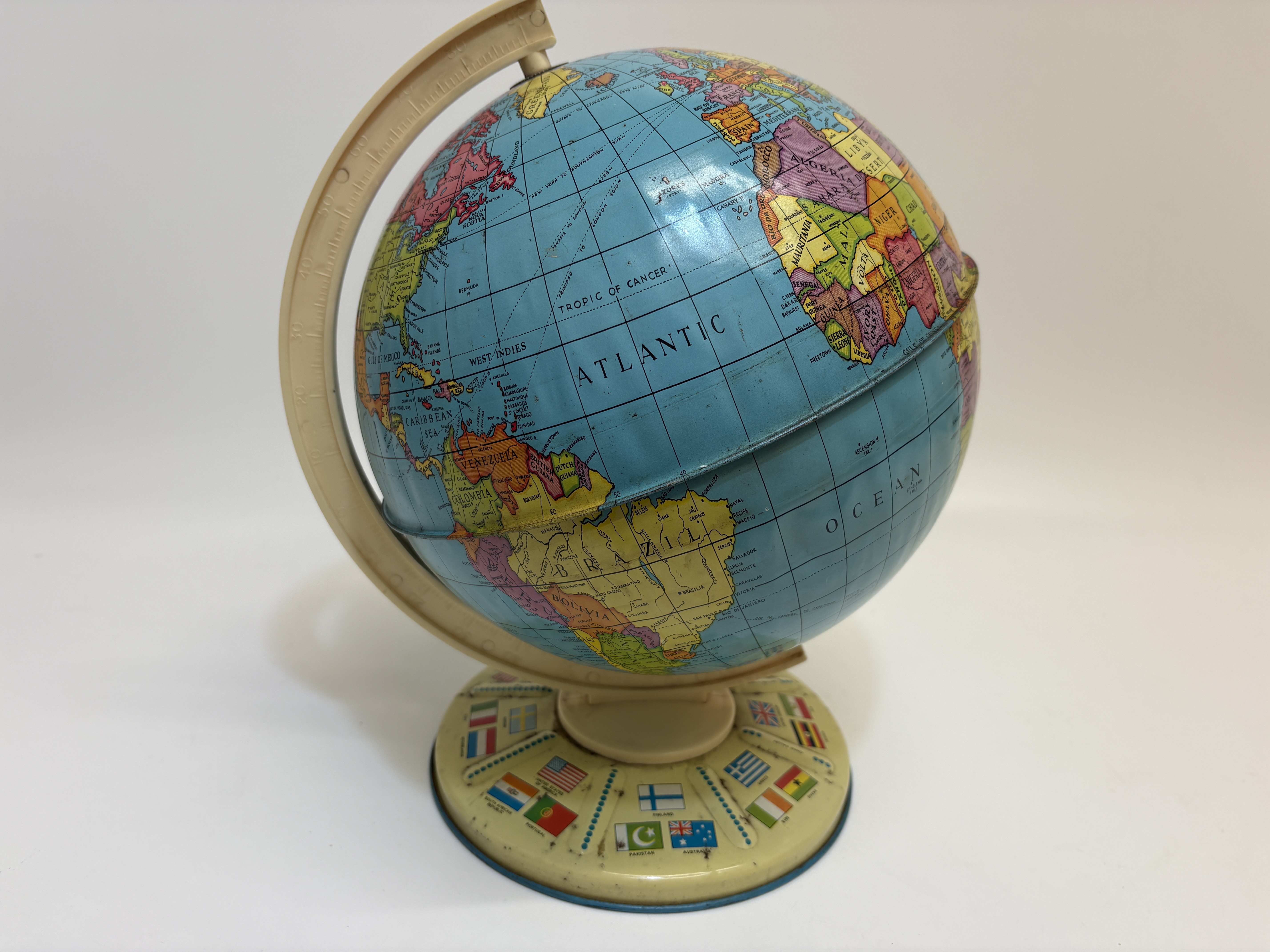 Vintage mid-1960s lithographed tinplate toy world globe with flag-motif base