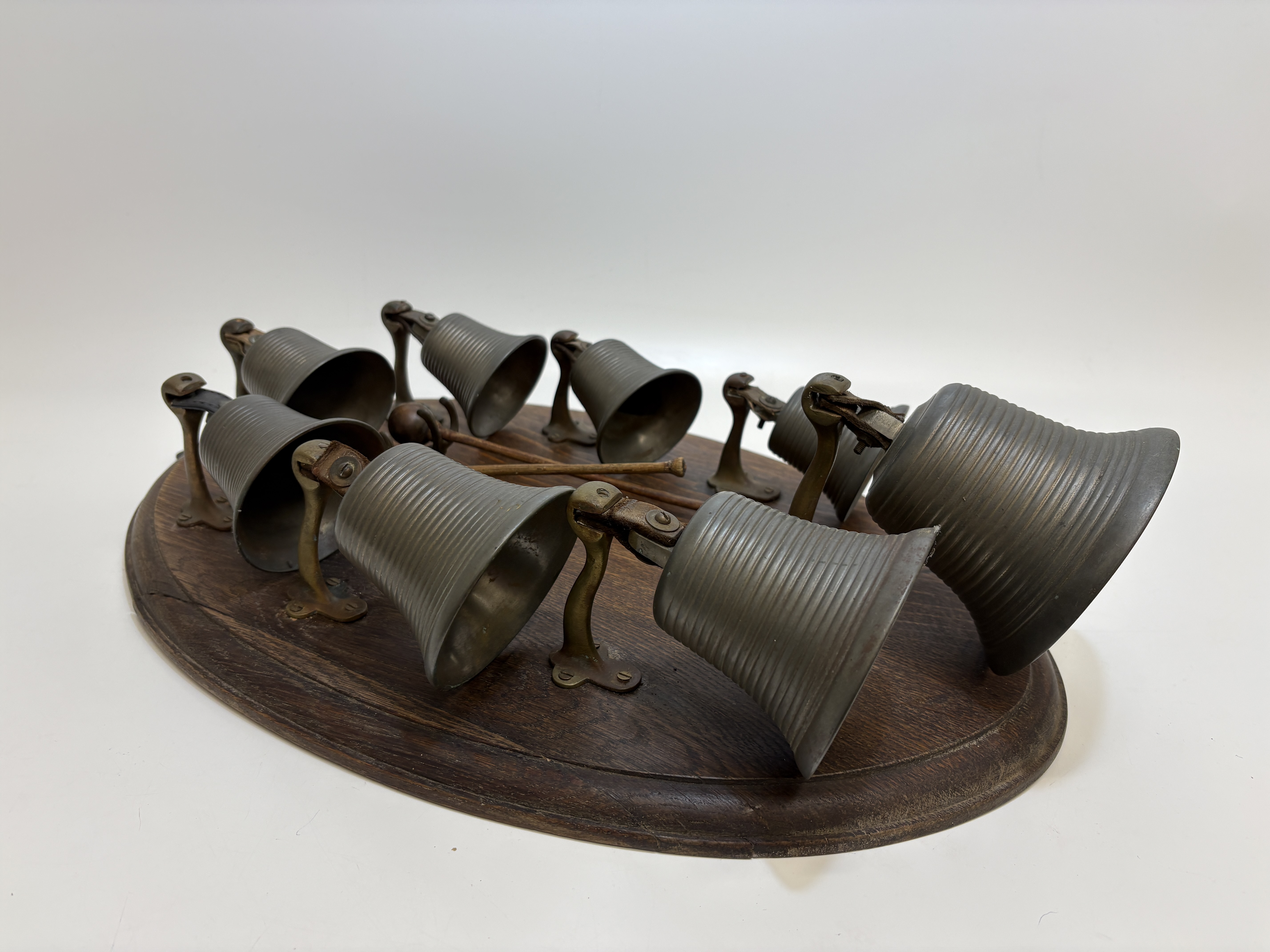 A set of eight graduated musical bronze bells by Morris mounted on an oak plaque