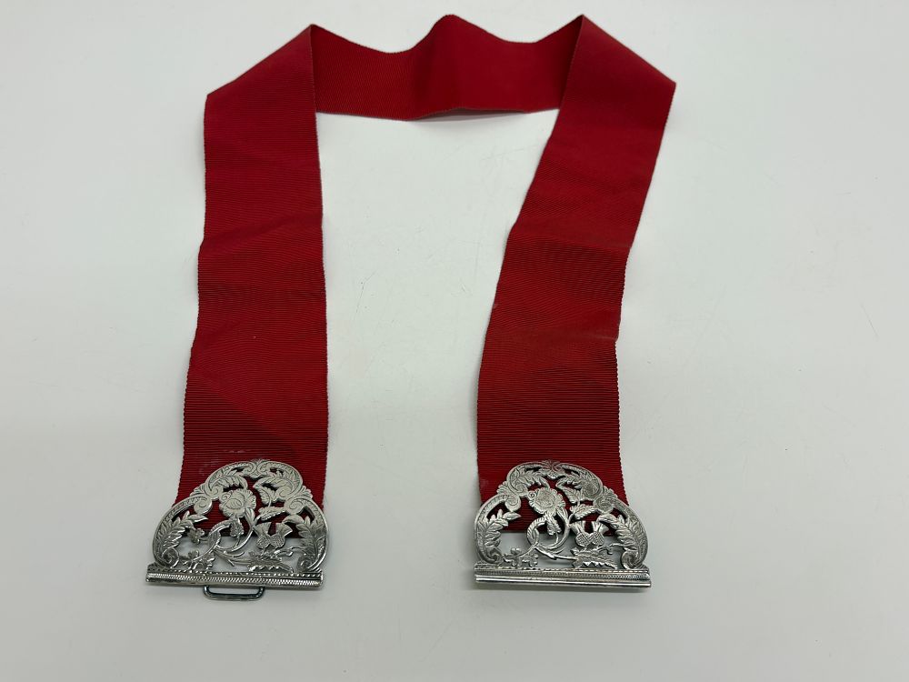 Lot 92: A hallmarked sterling silver nurses belt buckle on red grosgrain ribbon circa 50g gross