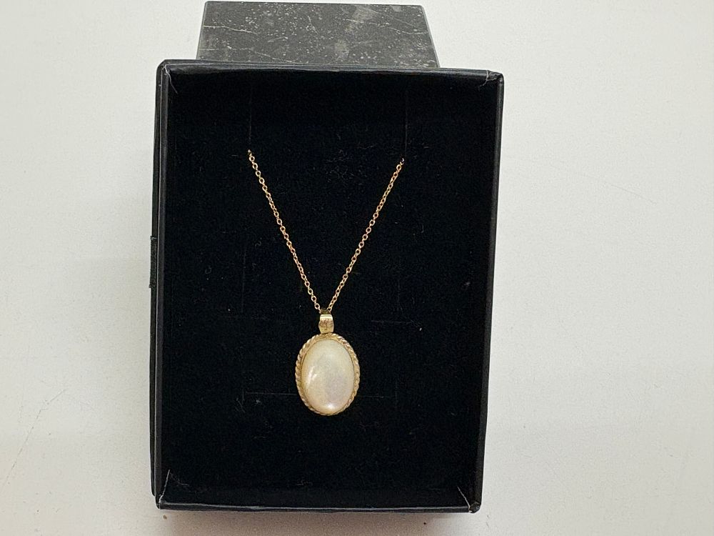 Lot 41: A 9 carat yellow gold and opal cabochon pendant with a gold plated chain