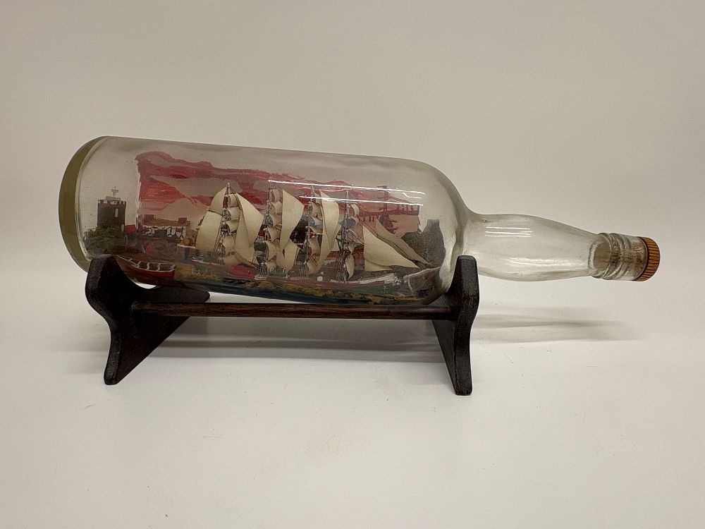 Lot 610: Vintage Hand-Crafted Ship in a Bottle Diorama with Coastal Village Scene and Wooden Stand