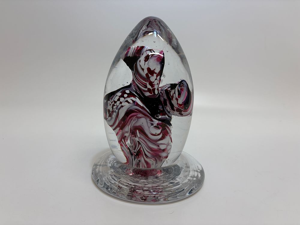 Lot 504: A hand-blown glass egg-shaped paperweight with internal maroon and white swirls 18cm