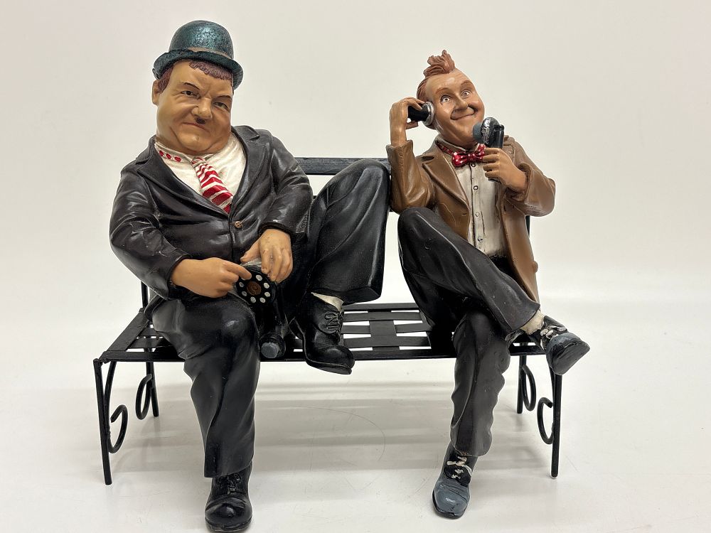 Lot 380: A Pair of Painted Composite Figural Groups Depicting Laurel and Hardy Seated on a Bench