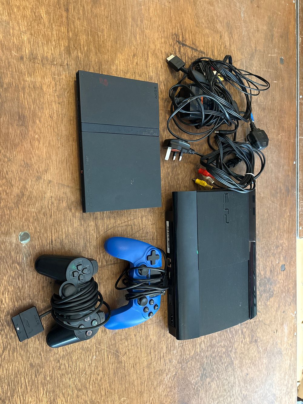 Lot 553: A Sony PlayStation 3 Super Slim Console and a Sony PlayStation 2 Slimline Console with Controllers, Cords, and a Collection of Games