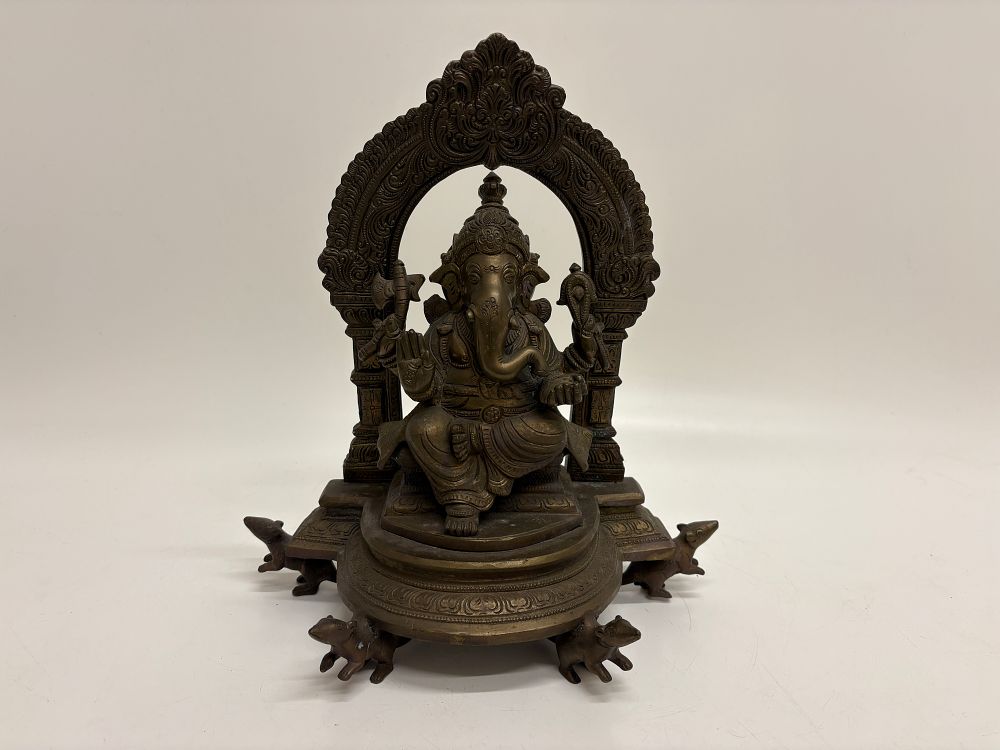 Lot 196: A cast metal Lord Ganesha idol seated on a rat supported throne with ornate prabhavali 30x27cm