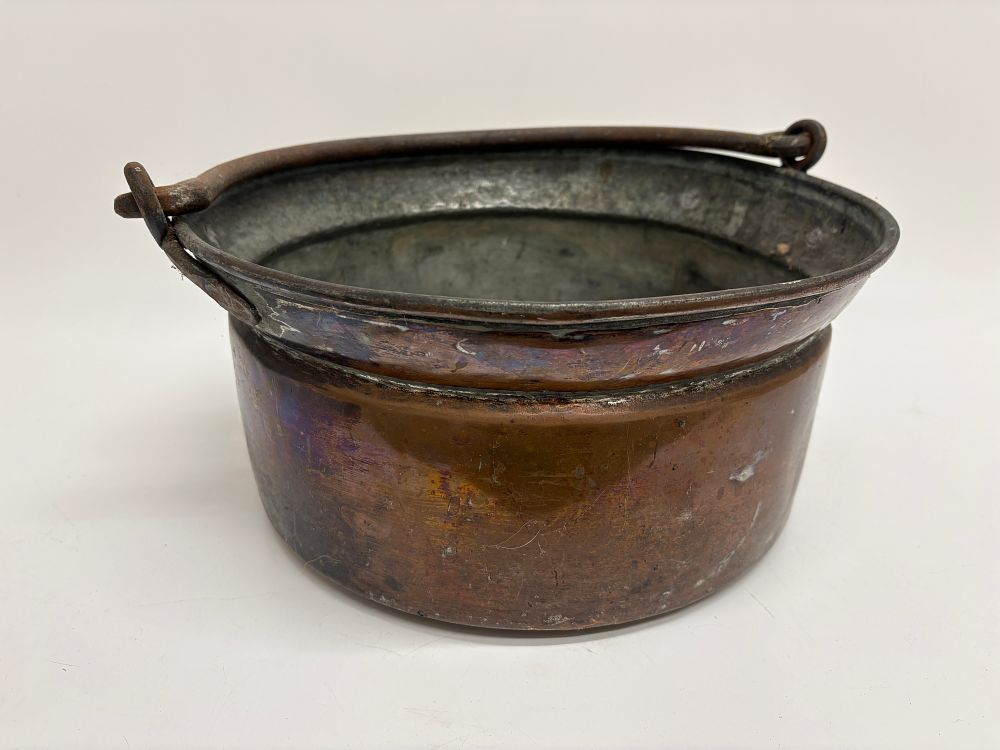 Lot 681: An antique hand hammered copper cauldron with hand forged iron swing handle