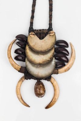 Boar Tusk Necklace. This necklace has boar tusks, possibly abalone, and cowrie shells on a woven