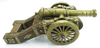 A BLACK POWDER CANNON. The barrel of brass with well-detailed modeling, the wooden carriage with 