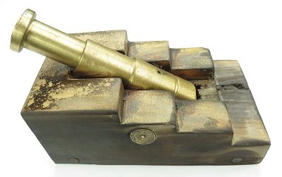 A BLACK POWDER CANNON. With stepped brass barrel and hardwood carriage, each side set with a 