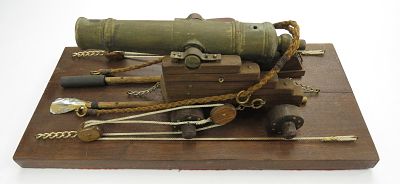 A BLACK POWDER CANNON. A detailed example, the massive turned brass barrel on its wooden 