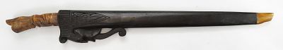 A SUMBAWAN SWORD. The carved bone handle in the form of a seated deity, the straight 