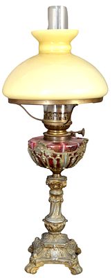 Petroleumlampe. rechteckiger mit Barock-Ornamenten verzierter Metallfu&szlig;, auf vier F&uuml;&szlig;en stehend 