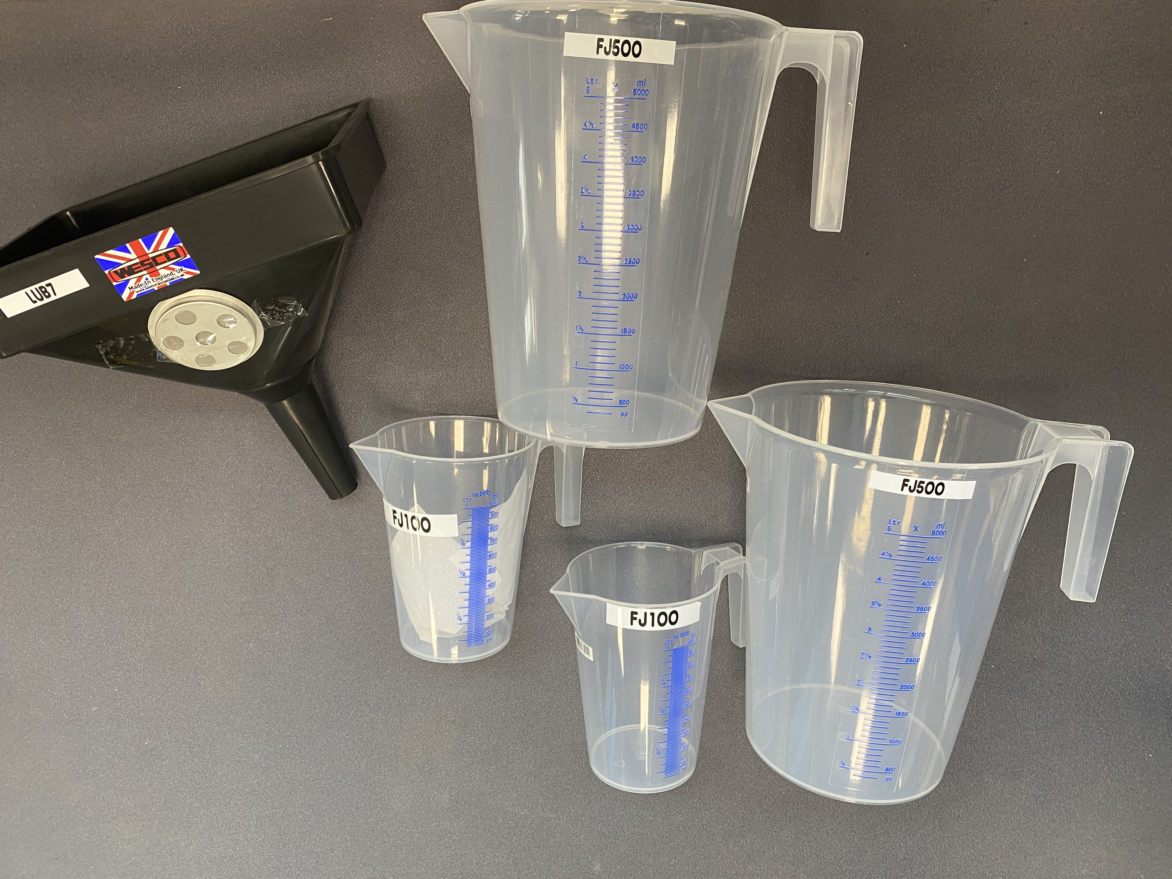 * A Set of Five Industrial Graduated Measuring Jugs and Wesco Filter Funnel
