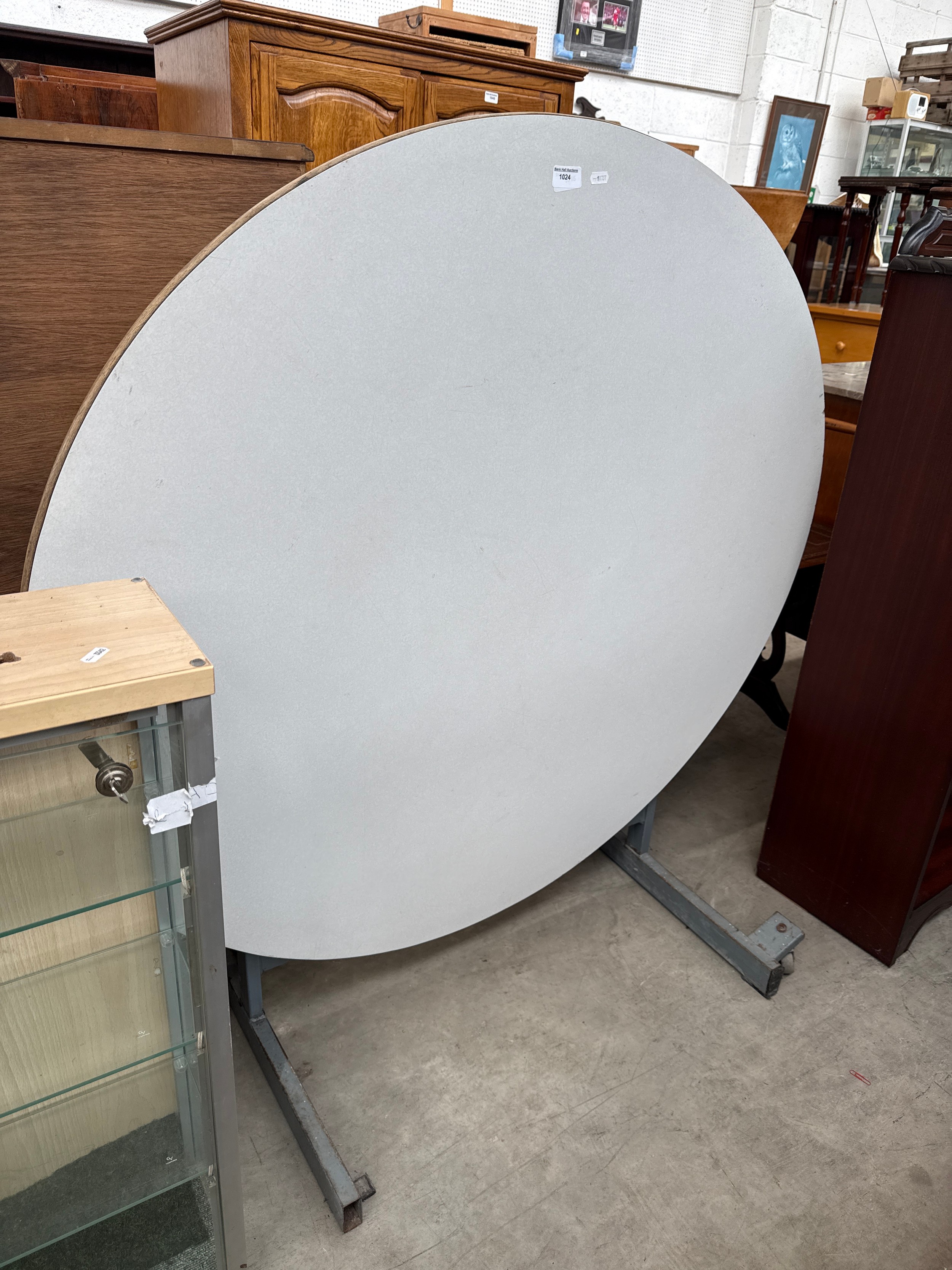 A large circular tilting events table on metal frame