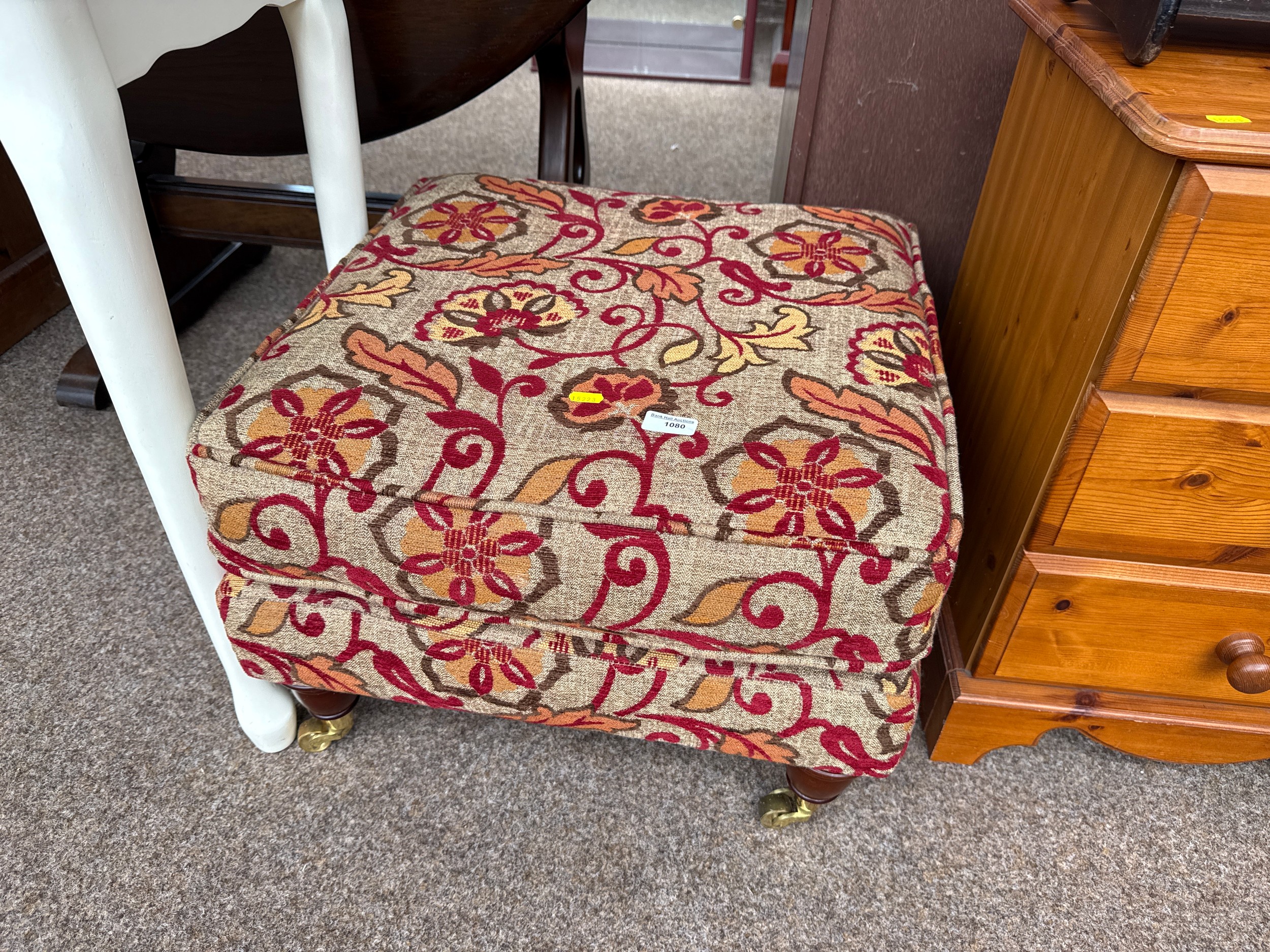 An upholstered vintage square pouffe stool on brass casters