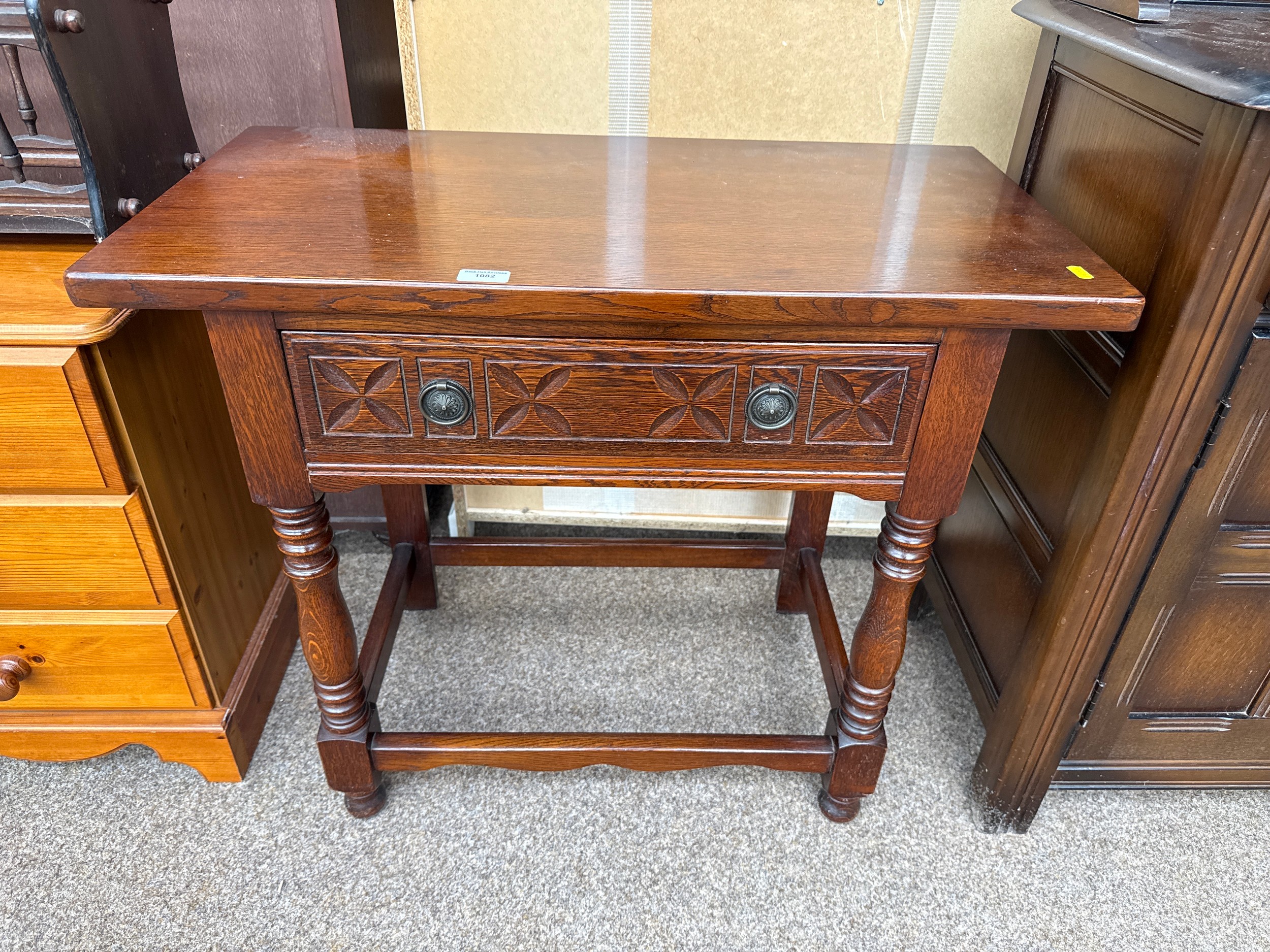 A vintage oak side table with carved drawer