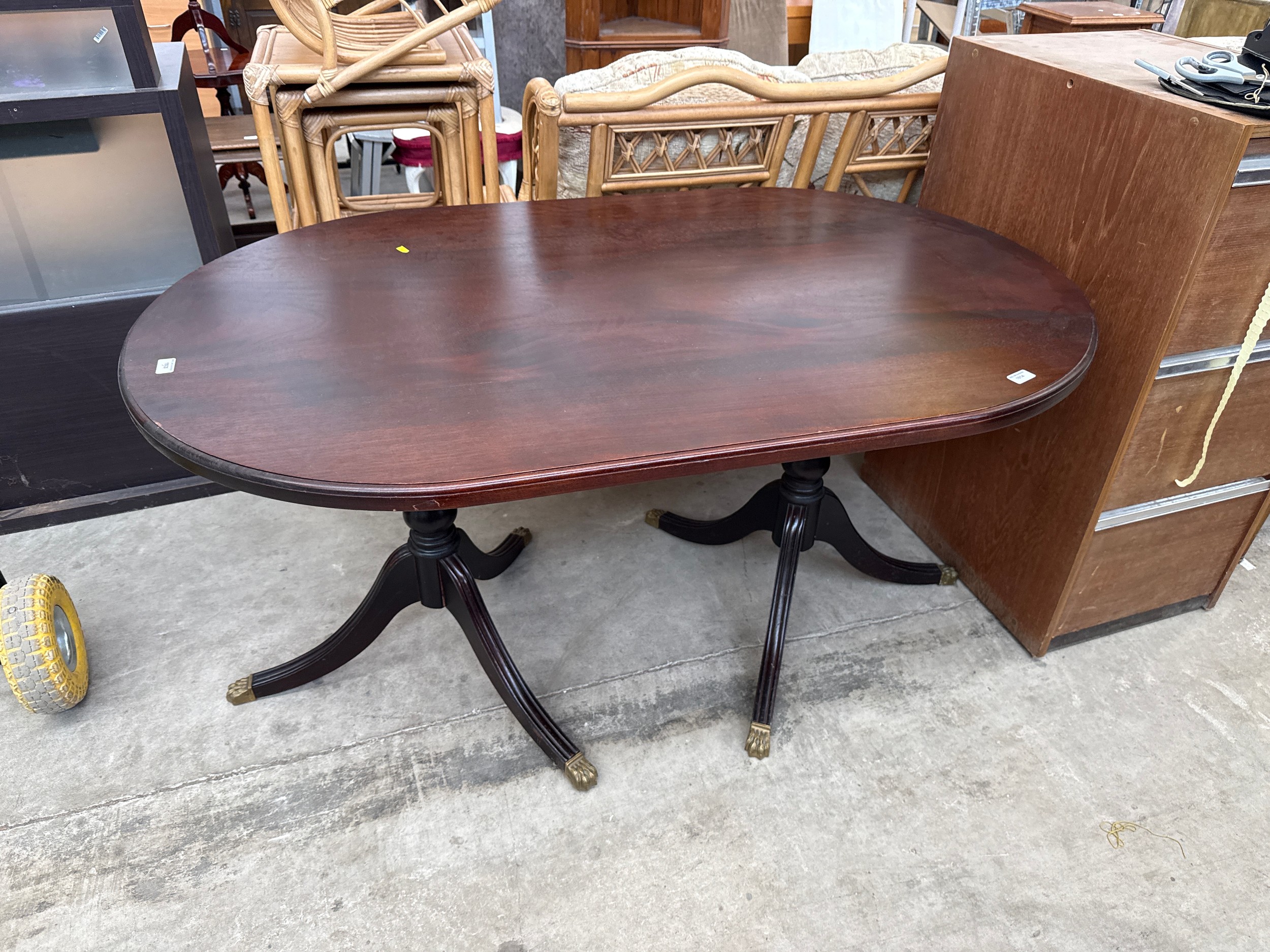 A large vintage oval mahogany dining table on splayed twin pedestal base