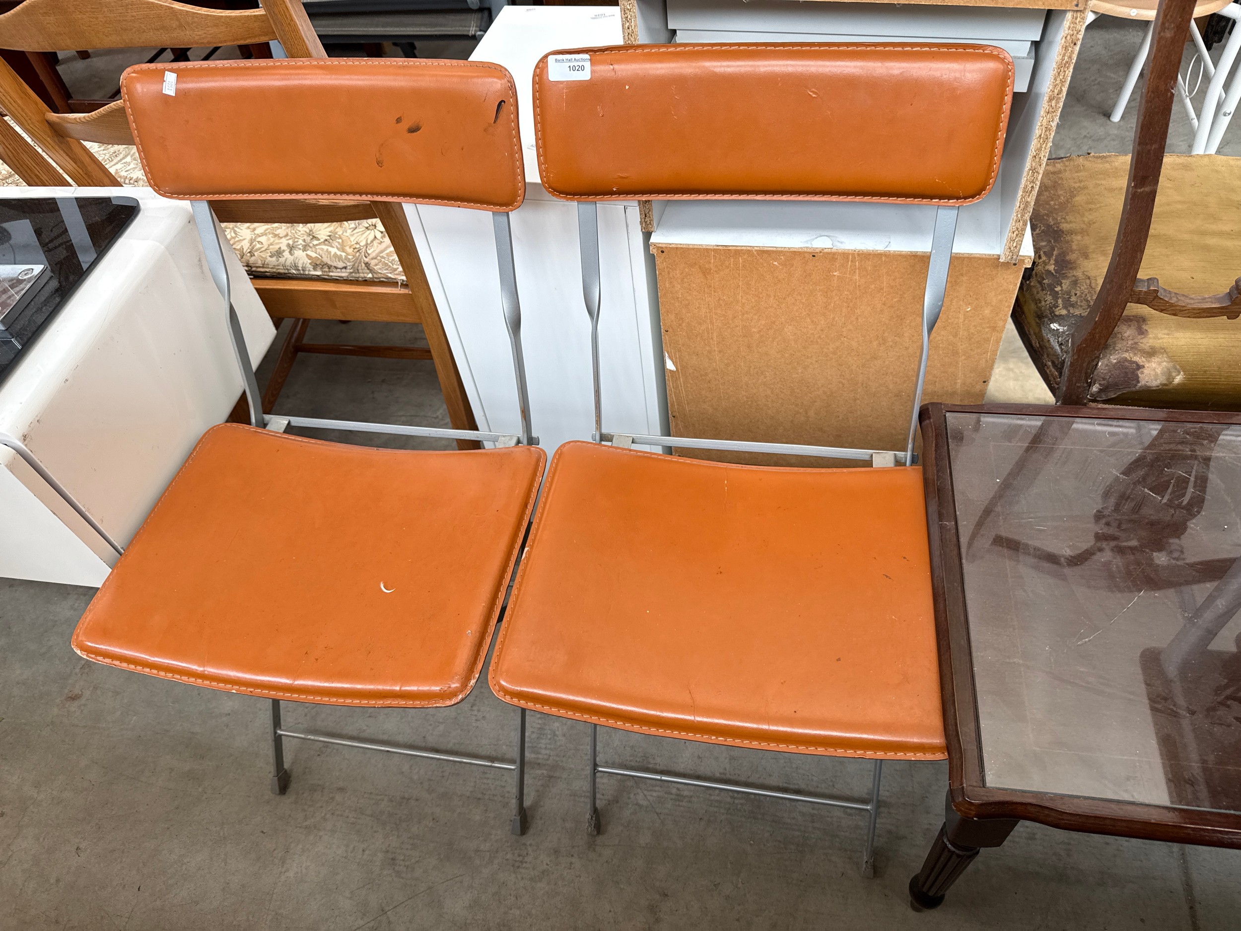 A pair of folding metal framed chairs with faux leather seats