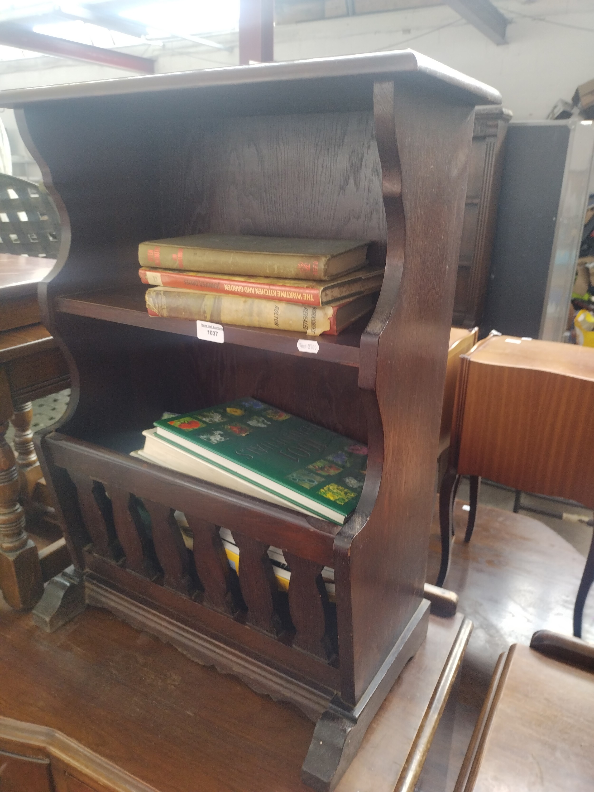 A vintage oak magazine rack stand with assorted books contents