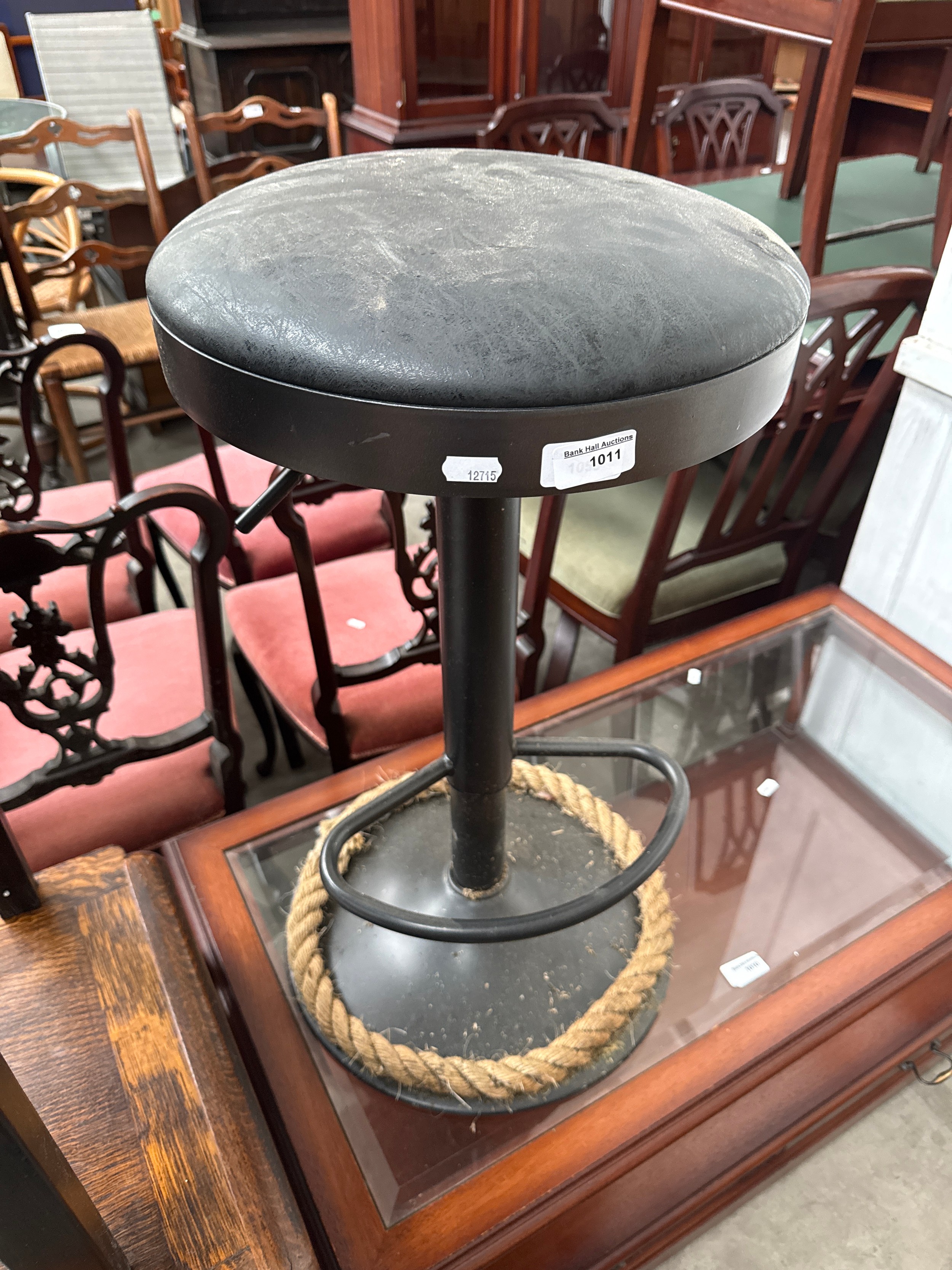 An adjustable metal bar stool with padded seat and rope decorated base