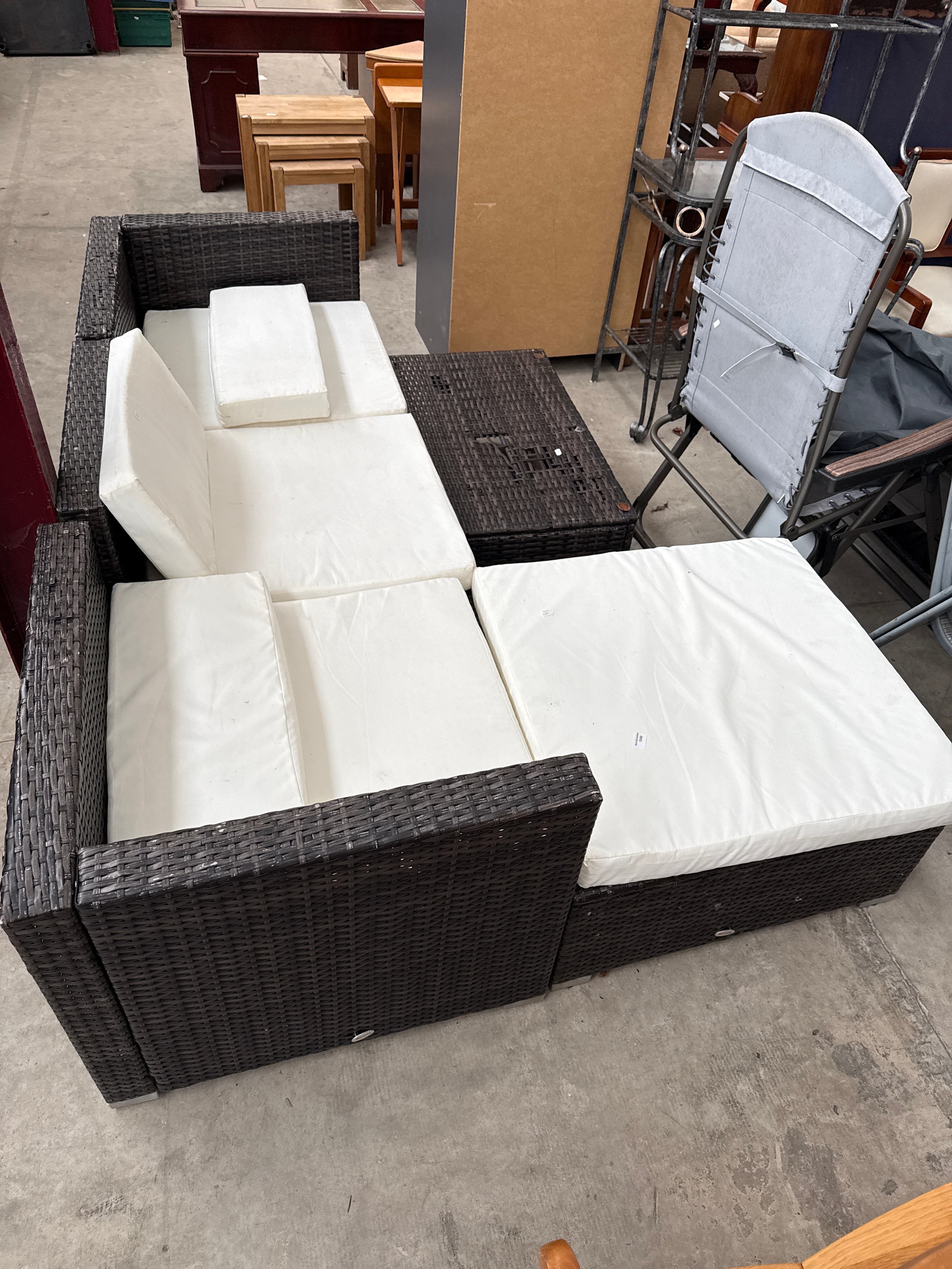 A large plastic woven corner seating patio set with table and cushions