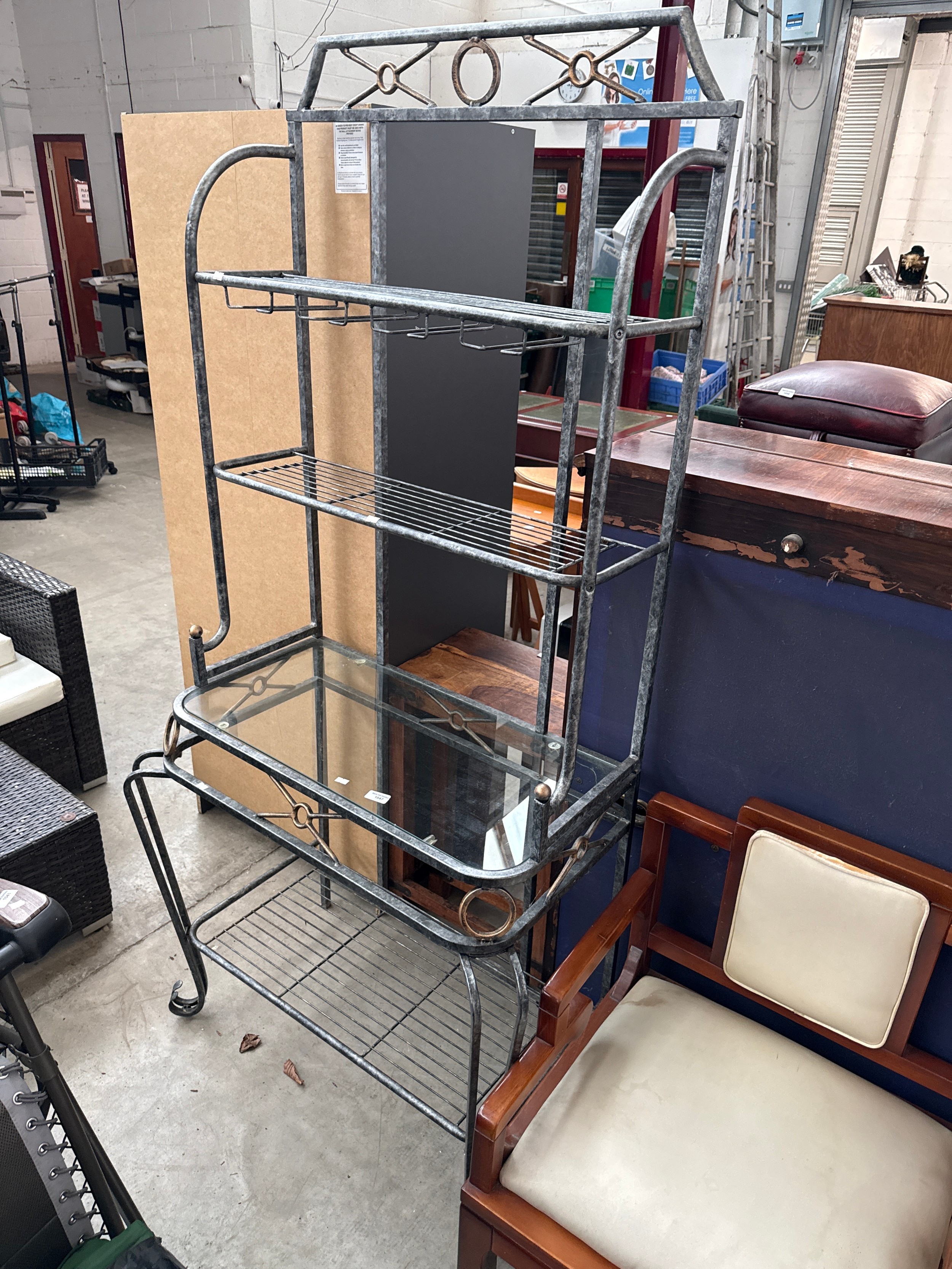 A large decorative metal framed hall stand with glass topped table and open
