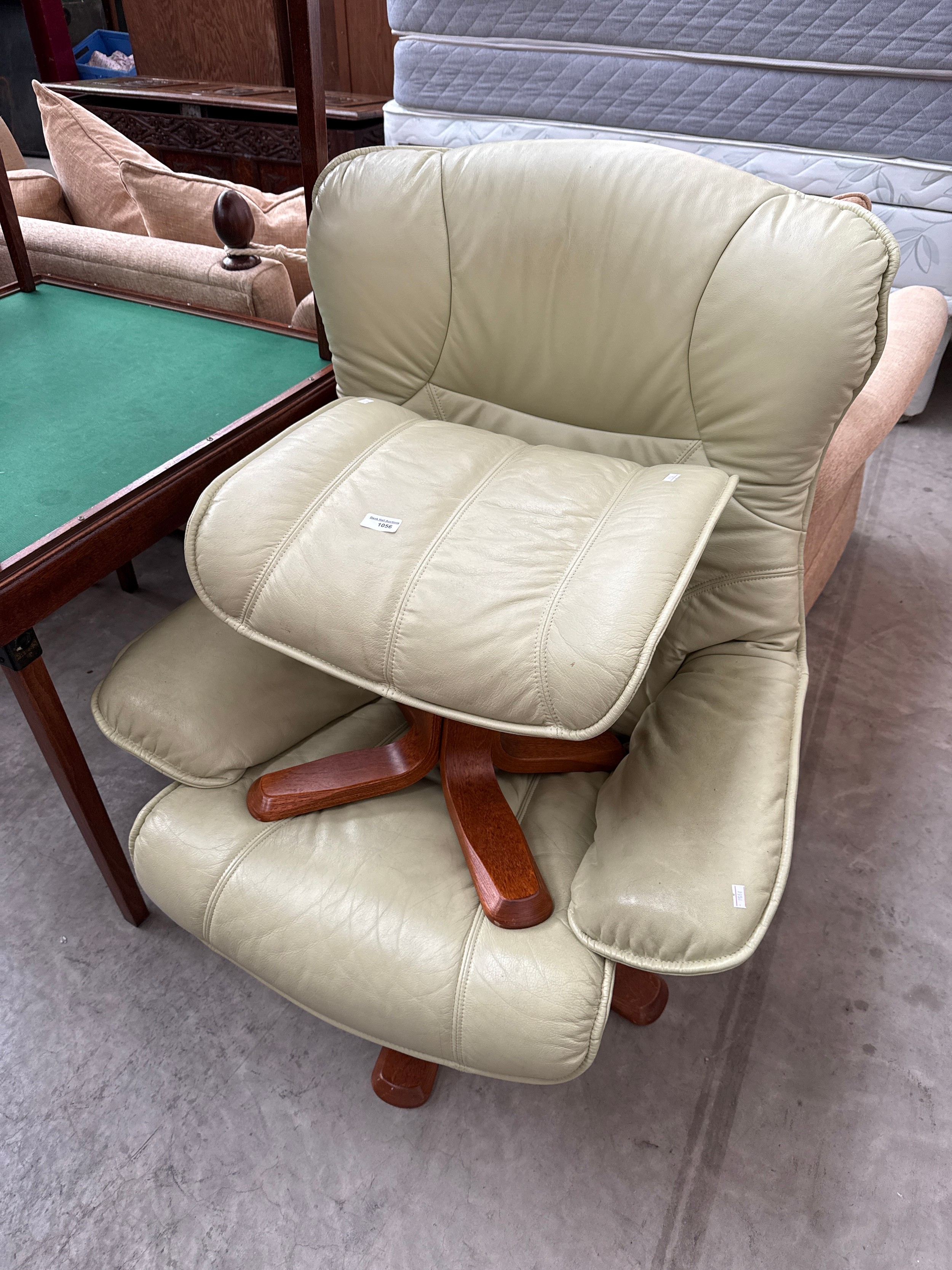 A padded leather swivel recliner chair with stool
