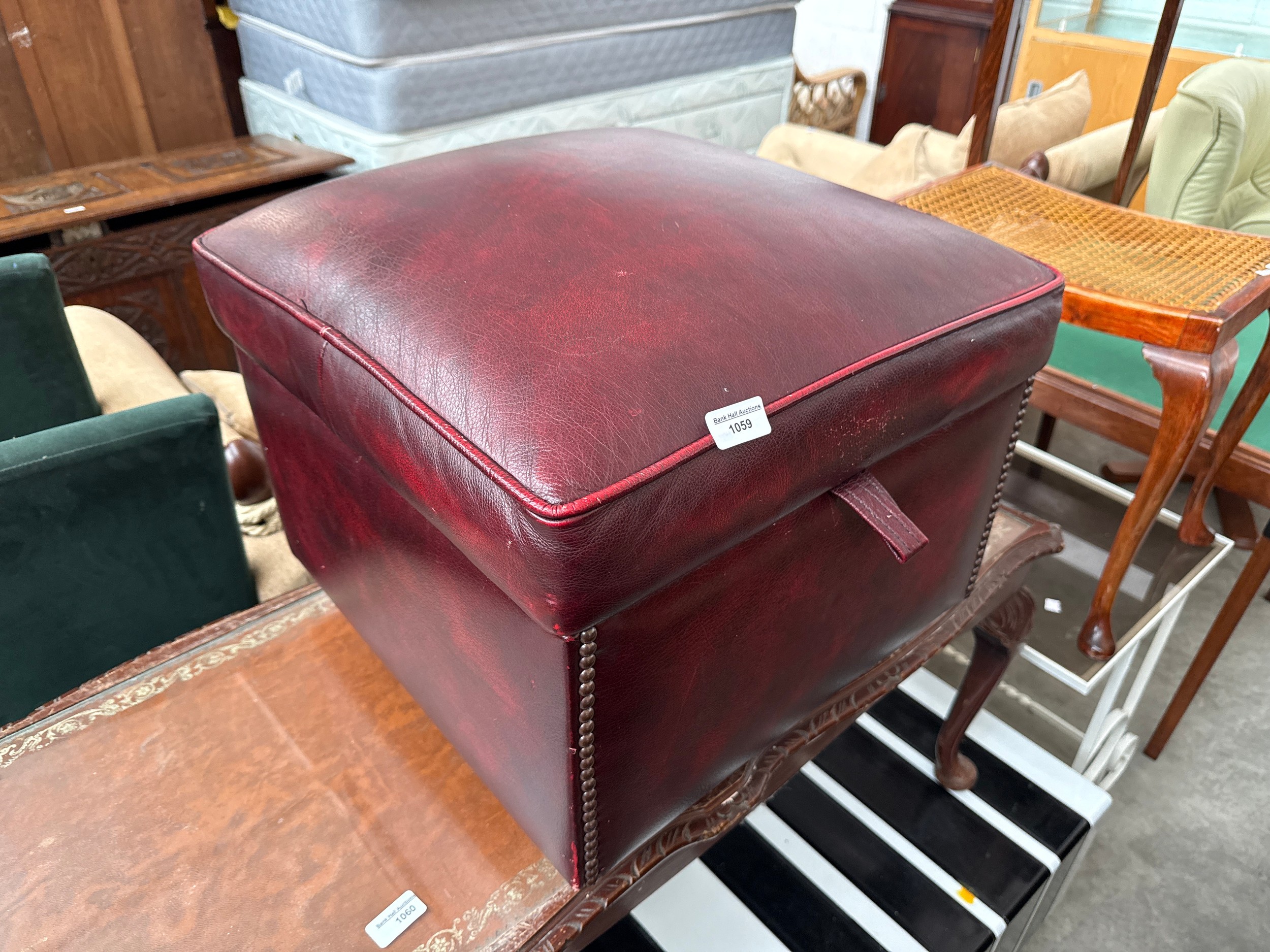 A padded burgundy leather storage box stool